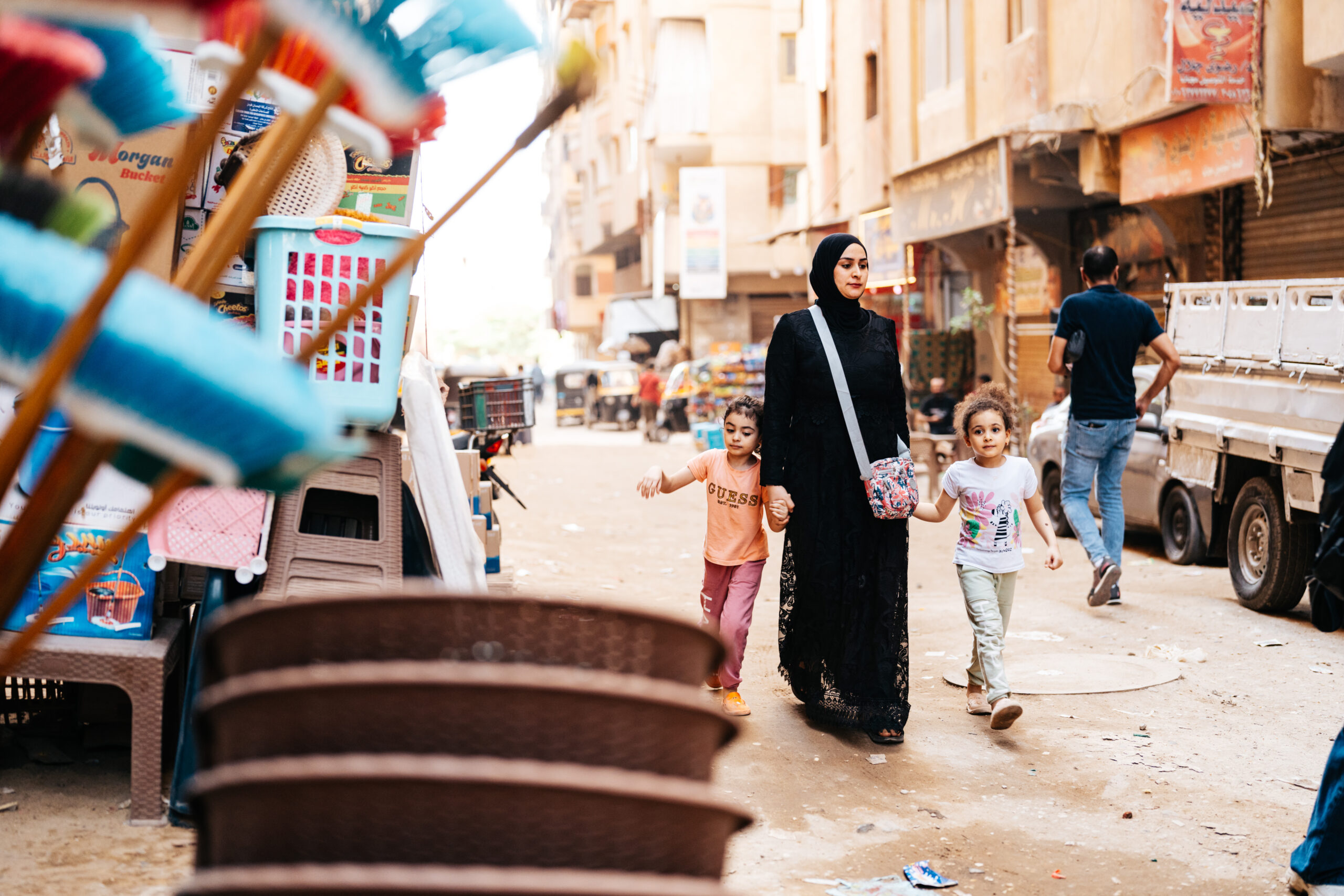A woman and two children walk through a market street, photographed during GCF’s broader humanitarian work in 2024.